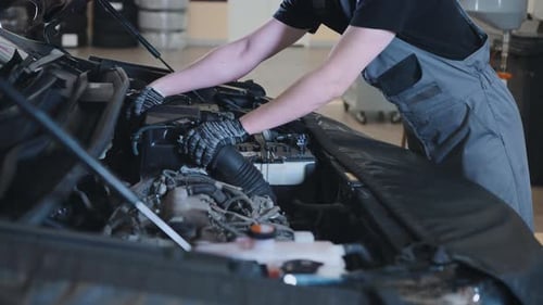 Unrecognizable Mechanic at a Service Station Checking the Engine