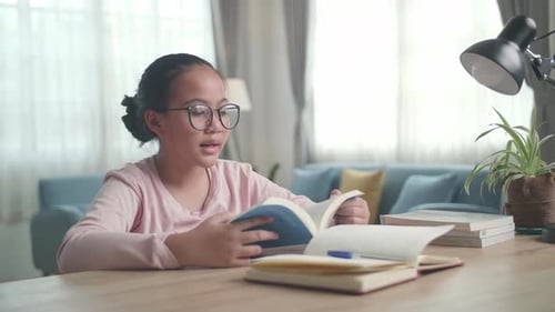 Girl Reading a Book at a Desk Indoors