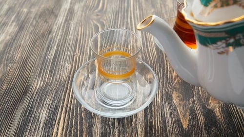 Pouring Golden Brown Tea into Clear Glass