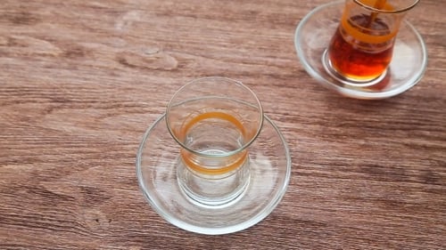 Pouring Turkish Tea into Glass on Wooden Table