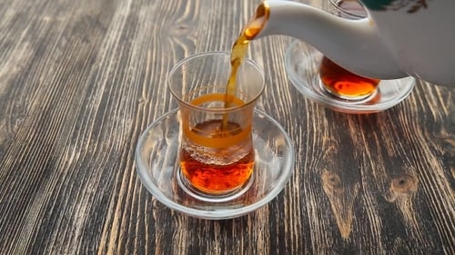 Pouring Tea Into Clear Glass Cup on Table