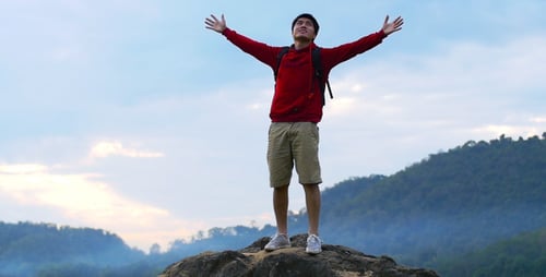 Hiker Reaches Mountain Summit Arms Outstretched