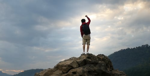 Hiker Climbing a Rocky Peak to Celebrate