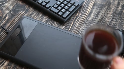 Graphic Designer Using Pen and Tablet at Workstation