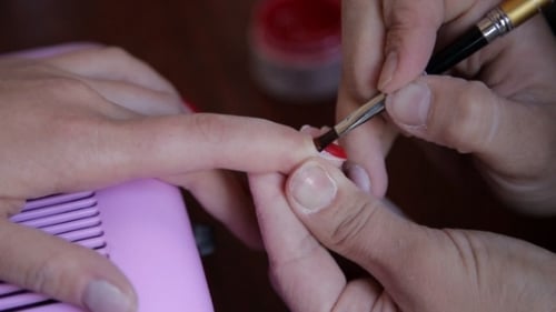 Hand Applies Red Nail Polish with Brush