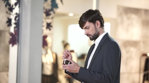 Man Looks at Engagement Ring in Boutique