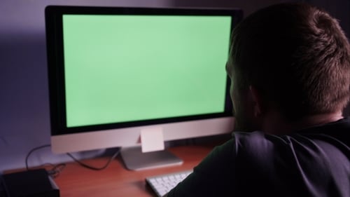 Hombre delante de la computadora con pantalla verde