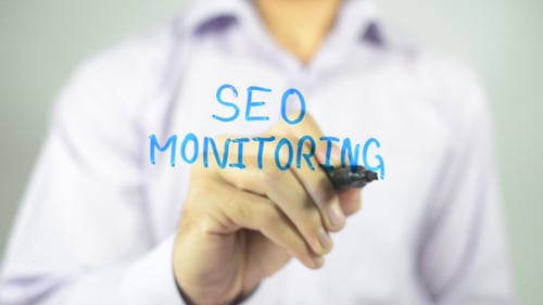 Man Writing SEO Monitoring on Clear Surface
