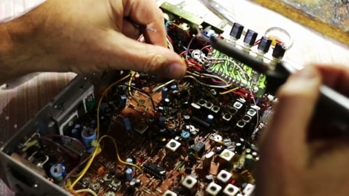Man Repairing Circuit Board with Soldering Iron