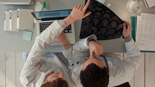 Doctors Reviewing Brain Scan at Desk in Hospital