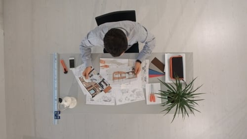 Ingenieur mit Bauplänen von Objekt und Laptop. Oben