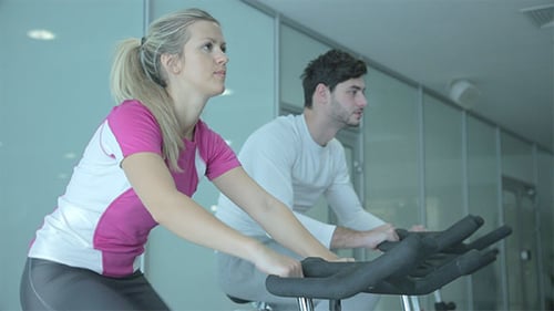 People Exercising on Stationary Bike at Gym