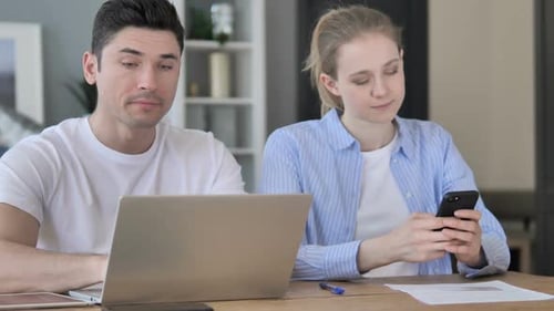 Man and Woman Working With Laptop and Smartphone