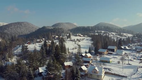 Malerische Landschaft der verschneiten Hügel mit Privathäusern und Bergen im Hintergrund