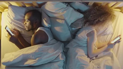 Man and Woman Using Mobile Phones before Sleep
