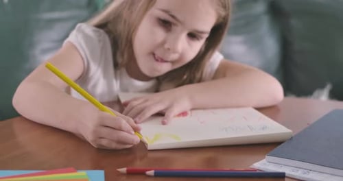 Retrato de primer plano de una niña caucásica concentrada dibujando, cámara moviéndose de la imagen a la del niño
