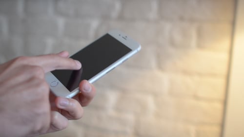 Hand Interacting with Silver Smartphone Close Up