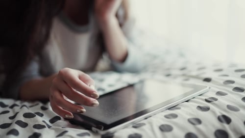 Woman Relaxing with Tablet on Bed
