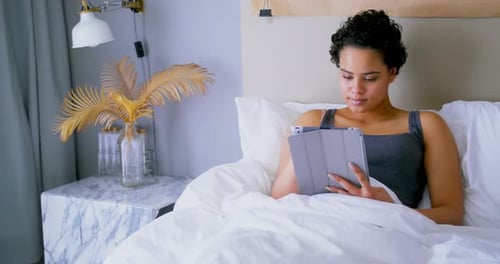 Woman Using Tablet in Bed at Home