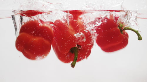Red Bell Peppers Splashing in Water, Close Up
