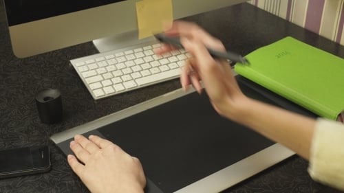 Person Using Graphic Tablet and Stylus at Desk