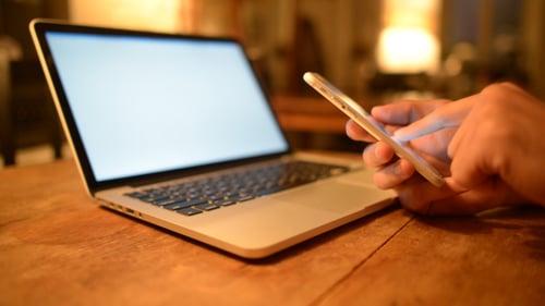 Using Smartphone and Laptop on a Wooden Desk