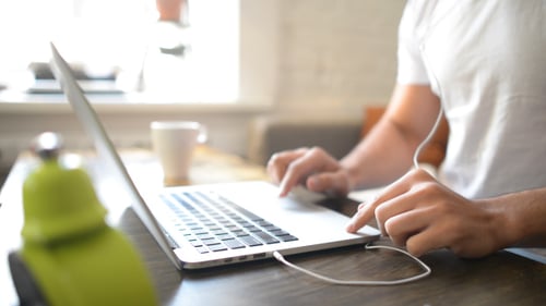 Adult Types on Laptop with Headphones Indoors