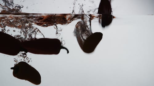 Red Peppers Falling Into Water in Studio