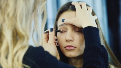 Makeup Artist Applying Eye Pencil on Young Woman