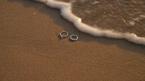 Wedding Rings on a Sandy Beach at Sunset