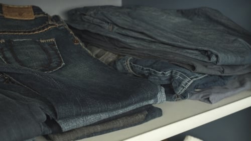 Stack of Blue Jeans on a White Shelf