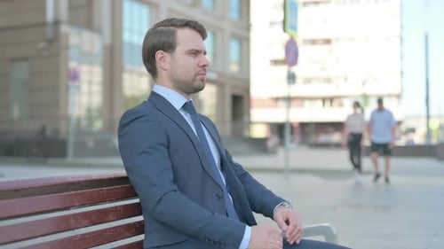 Man in Suit Sitting on Bench Outdoors