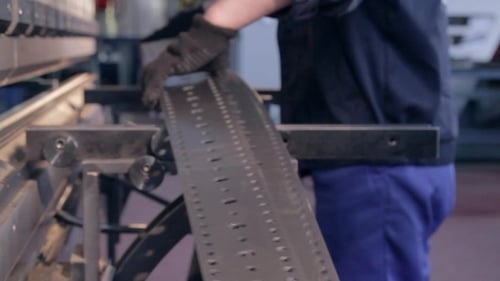 Worker places metal into industrial machine