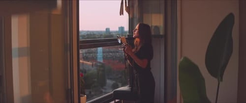 Woman Photographs City View with Vintage Camera on Balcony