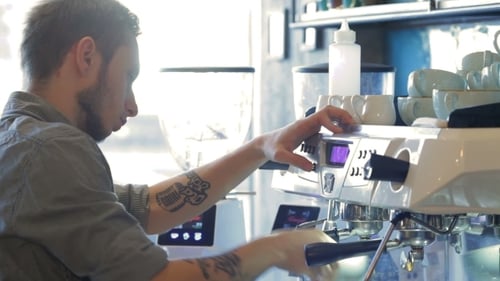 Young Adult Barista Making Espresso in Coffee Shop