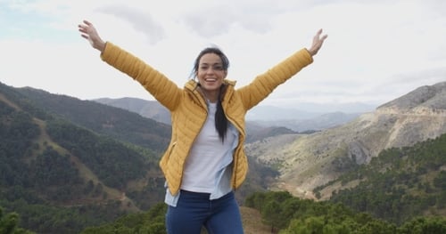 Woman Enjoys Mountain Views with Arms Raised
