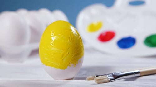 Pintando ovos de Páscoa com um pincel amarelo Preparação para a arte da celebração religiosa do feriado de