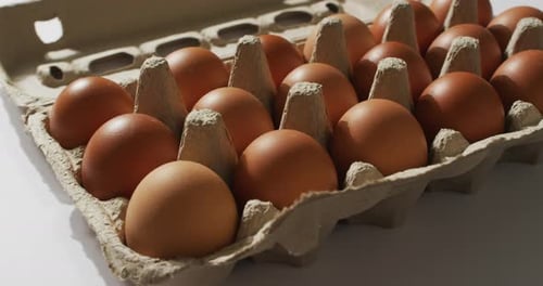 Nahaufnahme mehrerer Eier in einer Pappschachtel auf weißer Oberfläche