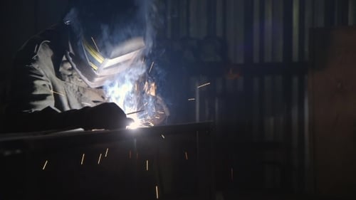 Welder Working on Metal in Dark Workplace