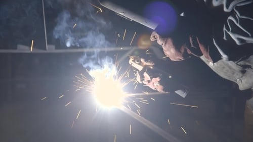 Welder Working with Sparks in Dark Environment