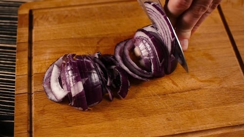 Woman Hands Slicing Onions On a Wooden Cutting Board
