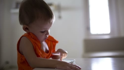 Engaged Toddler Interacts with Smartphone at Table