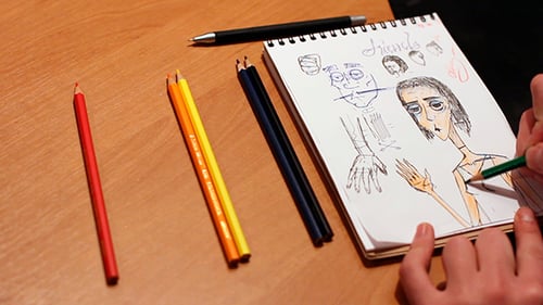 Hands Drawing a Colorful Sketch on Paper