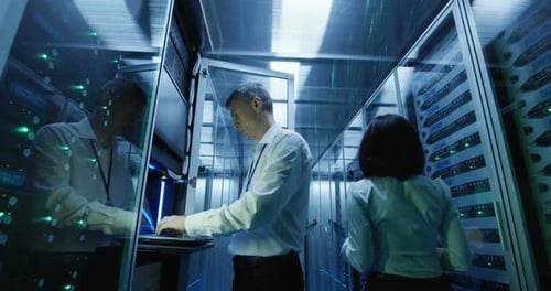 Technician Works on a Laptop in a Data Center