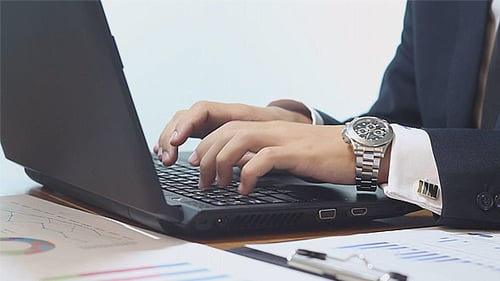 Businessman Typing on Laptop with Financial Charts
