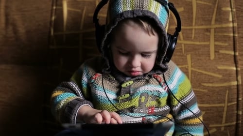 Adorable Child Enjoys Tablet with Headphones Indoors