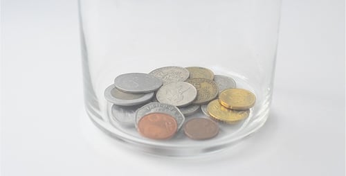 Coins Fall into Glass Jar in Close Up Shot