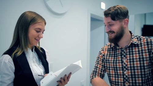 Woman Signing Document for Man in Office