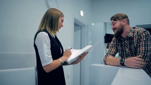 Woman Reviews Documents with Man at Office Counter