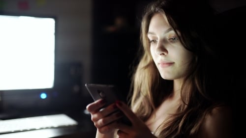 Woman Using Smartphone In City At Night
